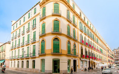 Facade of Picasso's Birthplace Museum in Málaga with green shutters and balconies.