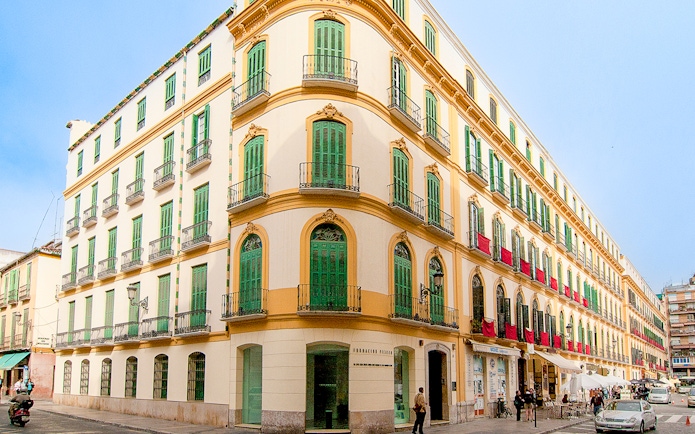 Facade of Picasso's Birthplace Museum in Málaga with green shutters and balconies.