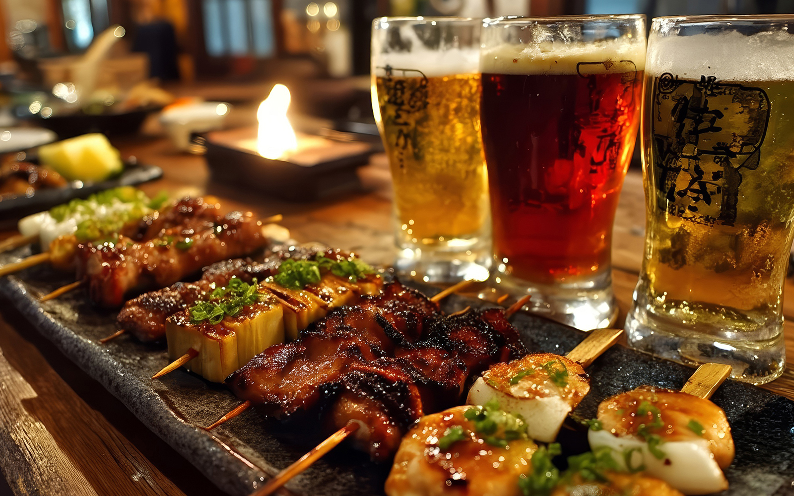 Yakitori skewers with beer glasses on a wooden table in a Japanese restaurant.