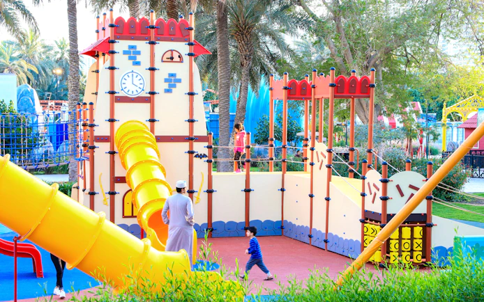 Children playing at Al Montazah Parks' Island of Legends playground with slides and climbing structures.