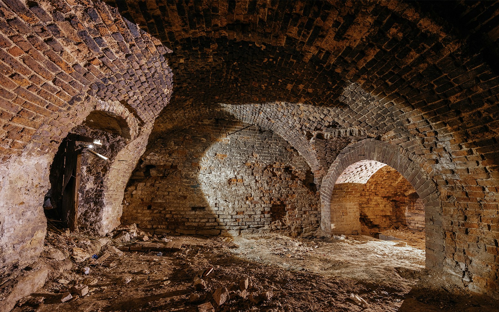 Old stone dungeon with arched ceilings and brick walls.