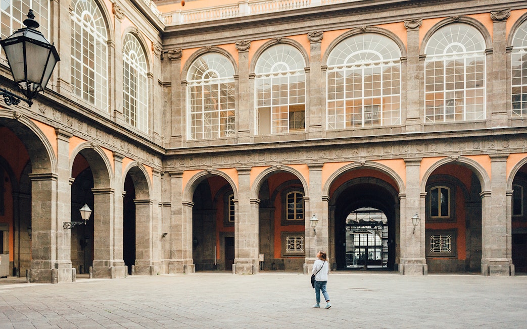 Woman walking in the courtyard of the Royal Palace of Naples, Italy.