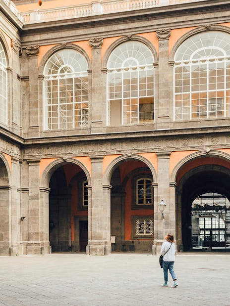 Woman walking in the courtyard of the Royal Palace of Naples, Italy.