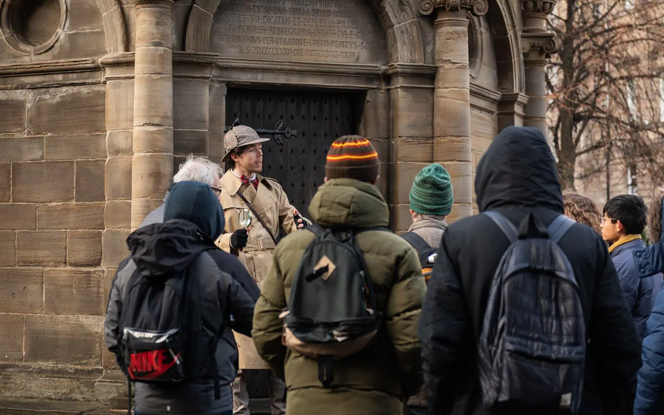 Tour guide in period costume leading a group at a historical site in Edinburgh.