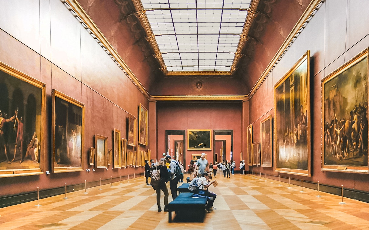 Visitors exploring artwork in the Denon Wing of the Louvre Museum, Paris.
