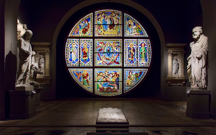 Stained glass window and statues inside Museo dell'Opera Siena