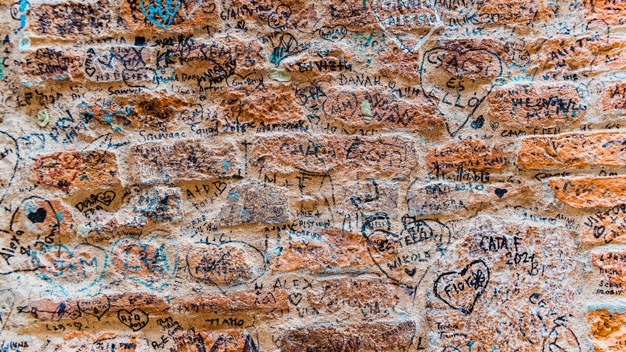 Graffiti-covered stone wall near Juliet's house in Verona, Italy.