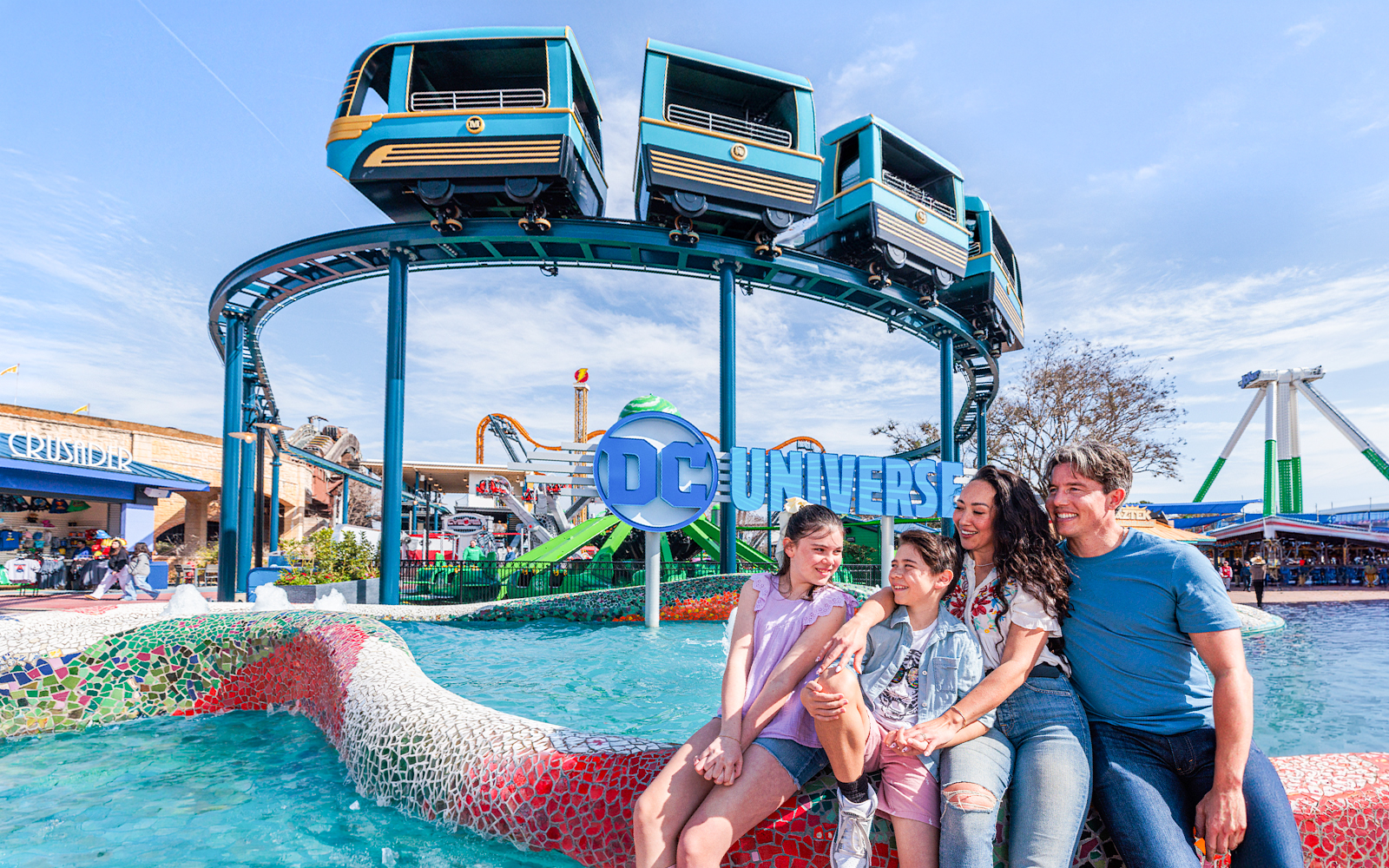 Family enjoying the DC Universe area at Six Flags Fiesta Texas with monorail above.