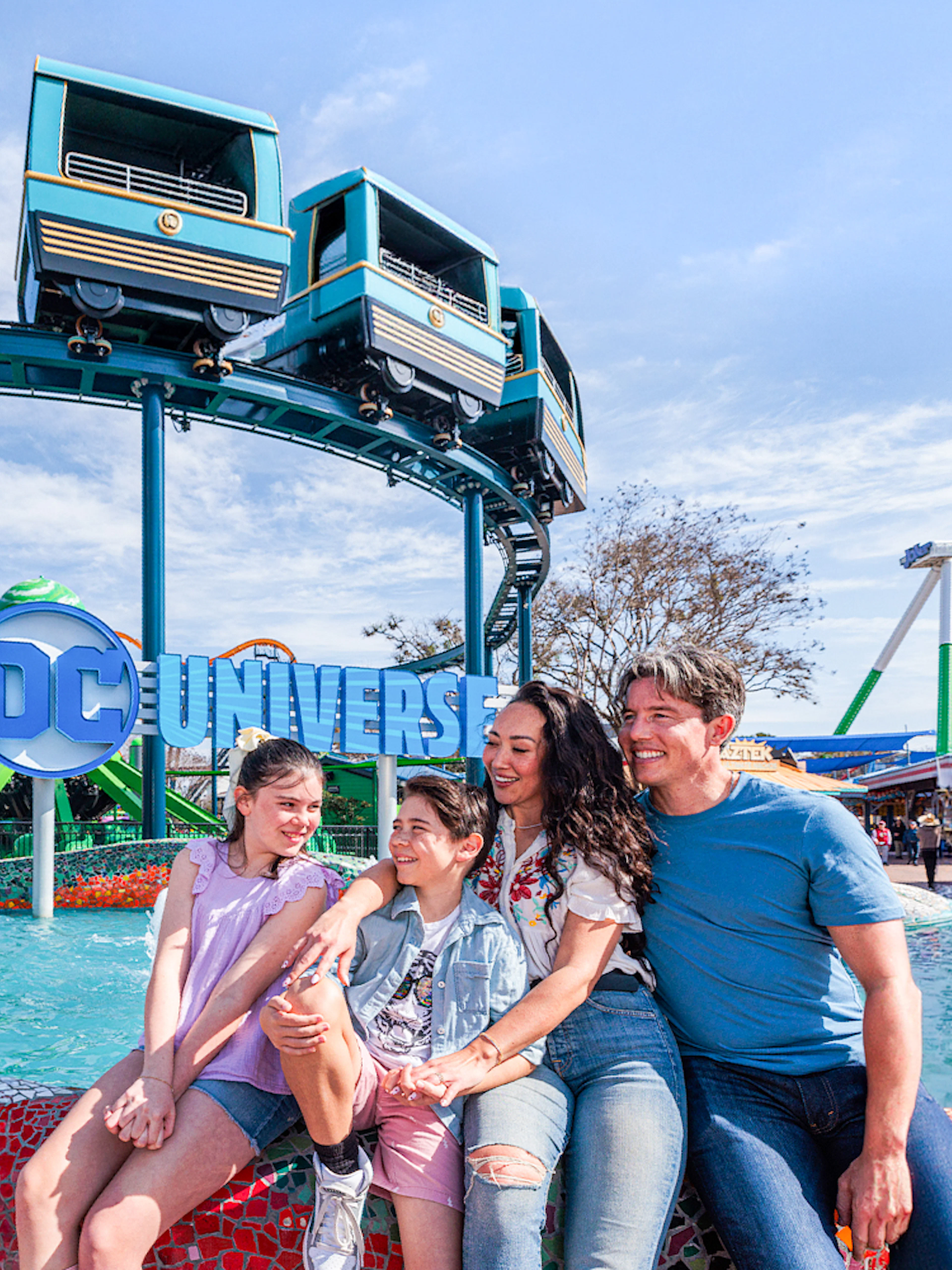 Family enjoying the DC Universe area at Six Flags Fiesta Texas with monorail above.
