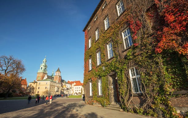 Wawel Castle courtyard with tourists on a guided tour in Krakow, Poland, enjoying a glass of wine.