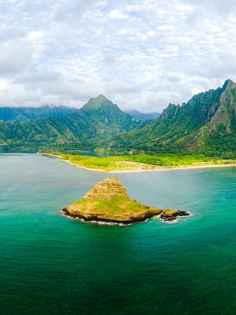 Aerial view of Kualoa Ranch, Hawaii with lush mountains and ocean.