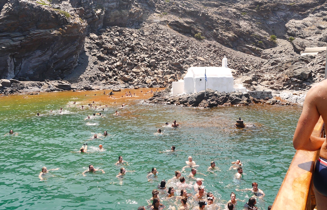 Guests swimming in Santorini hot springs during volcanic cruise tour.