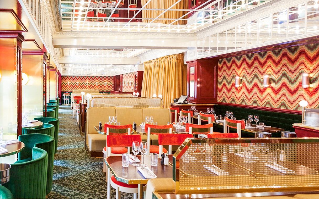 Dining area at Opéra-Grand Café Capucines in Paris with colorful decor and set tables.