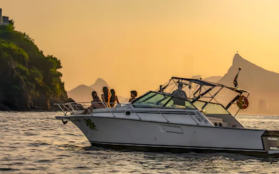 Tourists on a boat during Rio de Janeiro sunset cruise with Sugarloaf Mountain in the background.