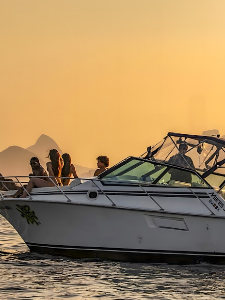 Tourists on a boat during Rio de Janeiro sunset cruise with Sugarloaf Mountain in the background.