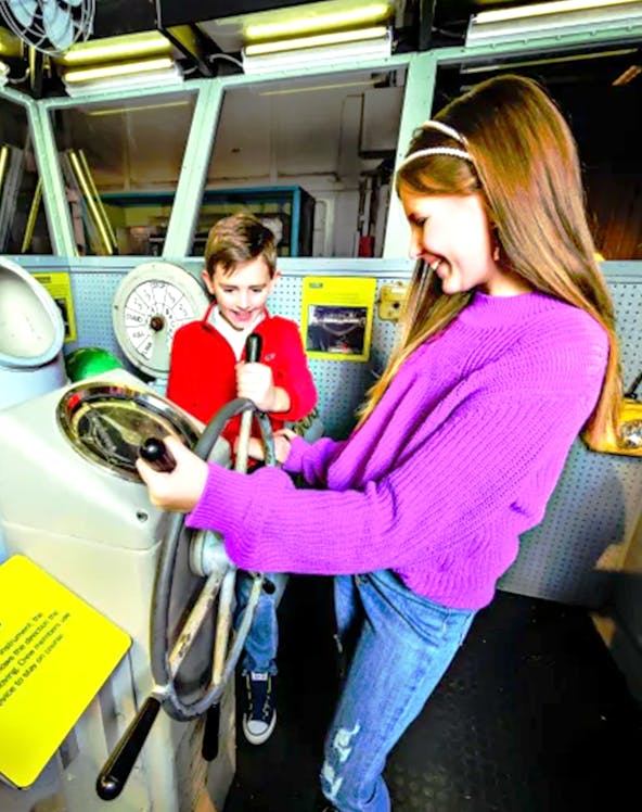 Children exploring ship controls at the Intrepid Museum, New York.