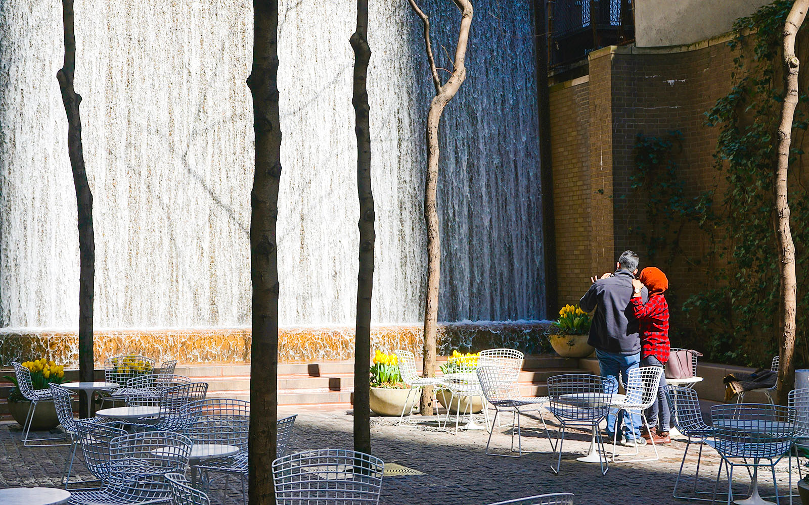 Couple standing near waterfall in Paley Park, New York City.