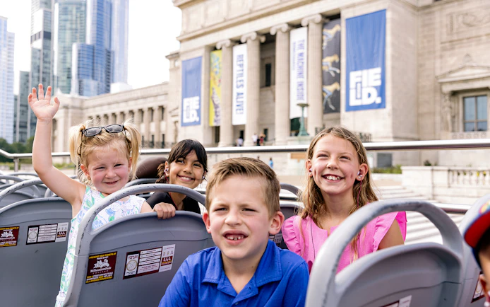 Children enjoying a hop-on hop-off bus tour in front of the Field Museum, Chicago.