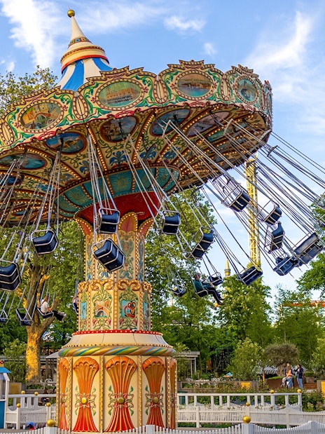 Swing ride at Tivoli Gardens, Copenhagen, with colorful seats and ornate design.