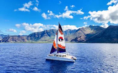 Catamaran sailing near Oahu mountains on Kaula Kai Snorkel Sail tour.