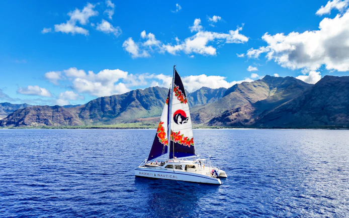 Catamaran sailing near Oahu mountains on Kaula Kai Snorkel Sail tour.