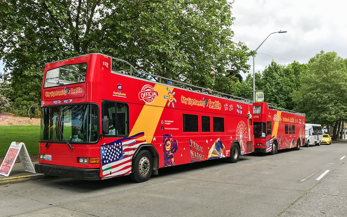 Seattle hop-on hop-off sightseeing bus parked on a tree-lined street.