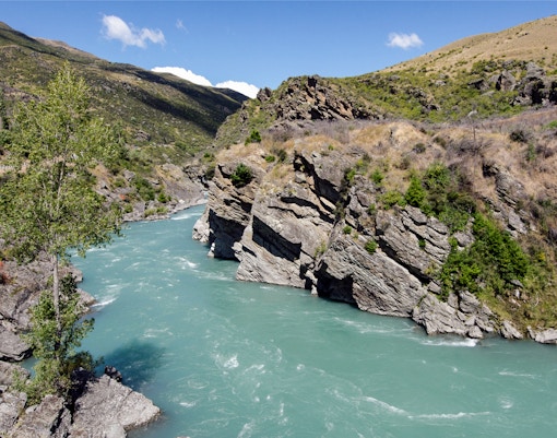 Skippers Canyon river with rocky cliffs and greenery, ideal for jet boat tours.