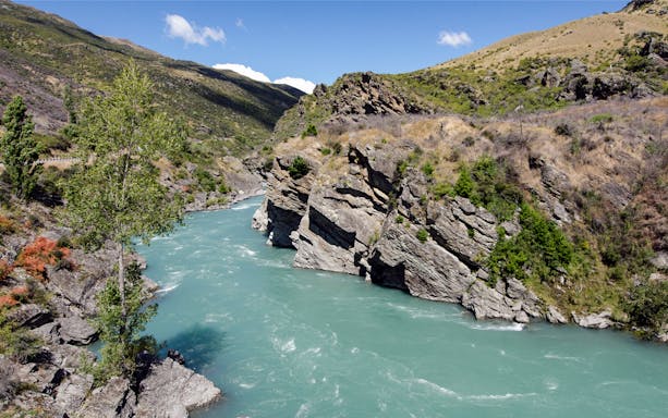 Skippers Canyon river with rocky cliffs and greenery, ideal for jet boat tours.