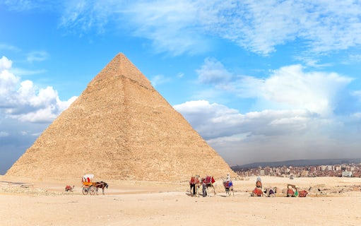 People walking with camels near the Pyramid of Giza, Egypt.