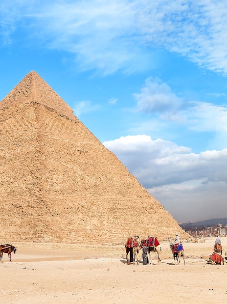 People walking with camels near the Pyramid of Giza, Egypt.