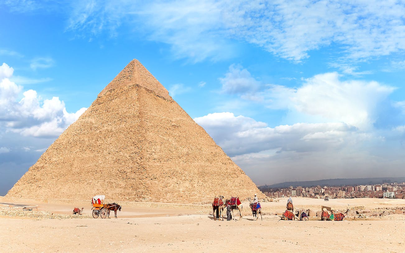 People walking with camels near the Pyramid of Giza, Egypt.