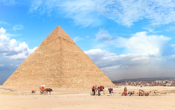 People walking with camels near the Pyramid of Giza, Egypt.