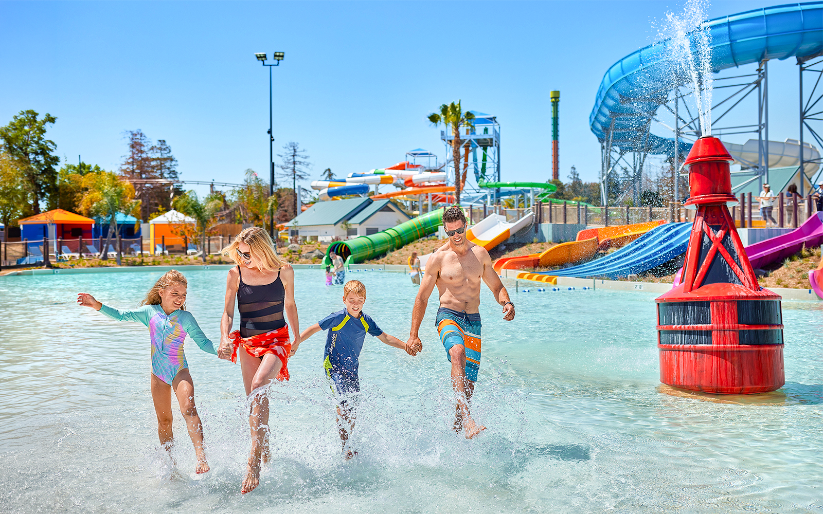 Family enjoying water park at South Bay Shores, California's Great America, with slides in background.