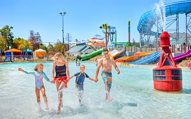 Family enjoying water park at South Bay Shores, California's Great America, with slides in background.