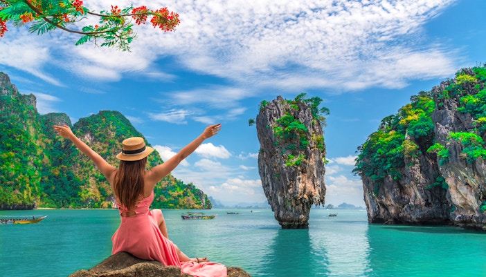 Woman enjoying view of Phang Nga Bay Islands with limestone cliffs and turquoise water.