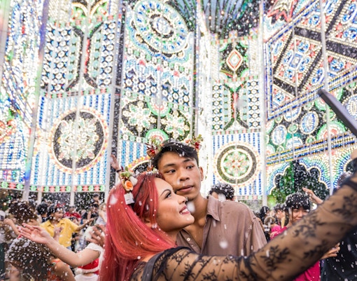 Couple taking selfie at Christmas Wonderland, GBB Cloud Forest with festive lights and snow.