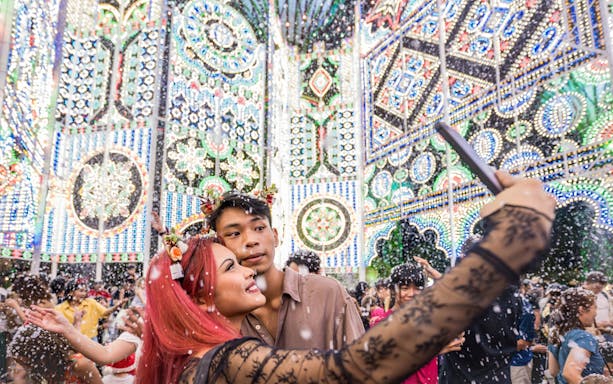 Couple taking selfie at Christmas Wonderland, GBB Cloud Forest with festive lights and snow.