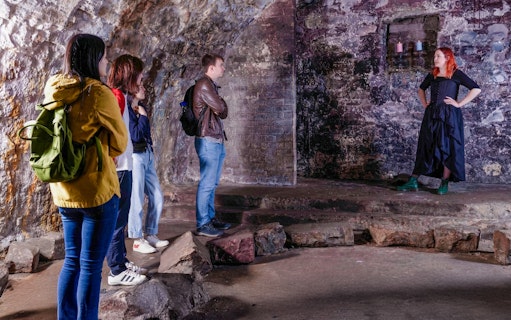 Tour group listening to a guide in the historic Edinburgh Vaults.
