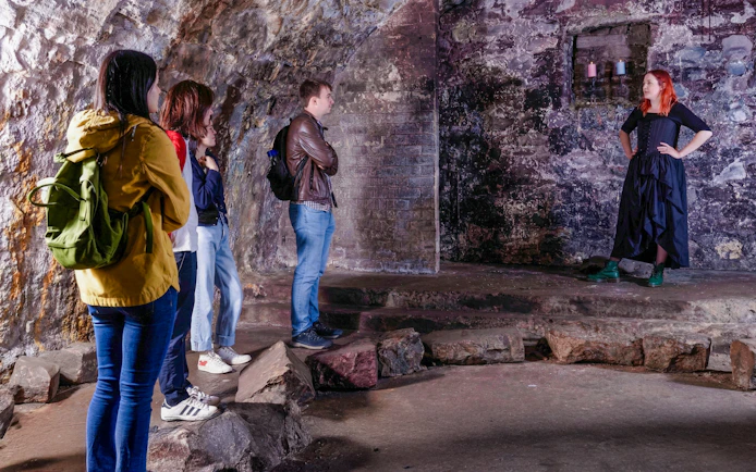 Tour group listening to a guide in the historic Edinburgh Vaults.