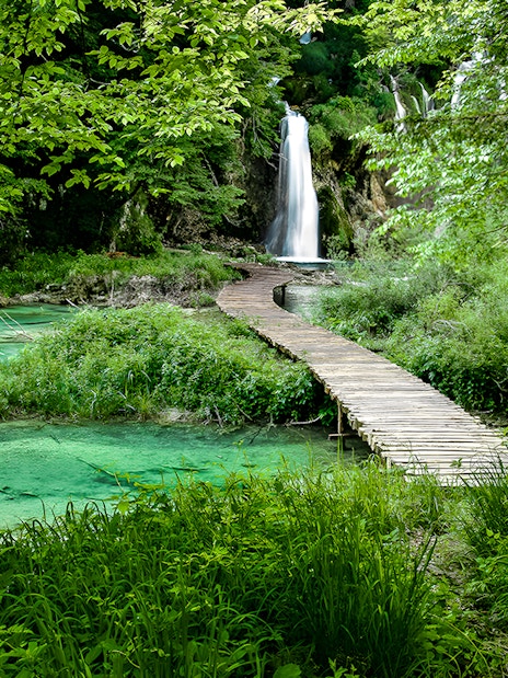 Wooden path leading to a waterfall at Plitvice Lakes National Park, Croatia.