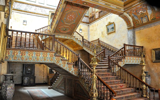 Ornate staircase inside Istanbul Beylerbeyi Palace with intricate woodwork and decorative ceilings.