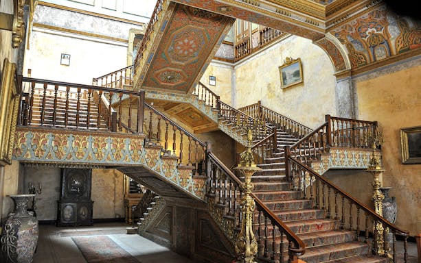 Ornate staircase inside Istanbul Beylerbeyi Palace with intricate woodwork and decorative ceilings.