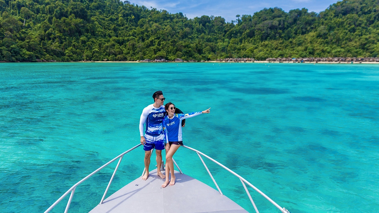 Couple on speedboat enjoying view of Surin Island's turquoise waters, Phuket day trip.