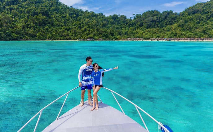 Couple on speedboat enjoying view of Surin Island's turquoise waters, Phuket day trip.