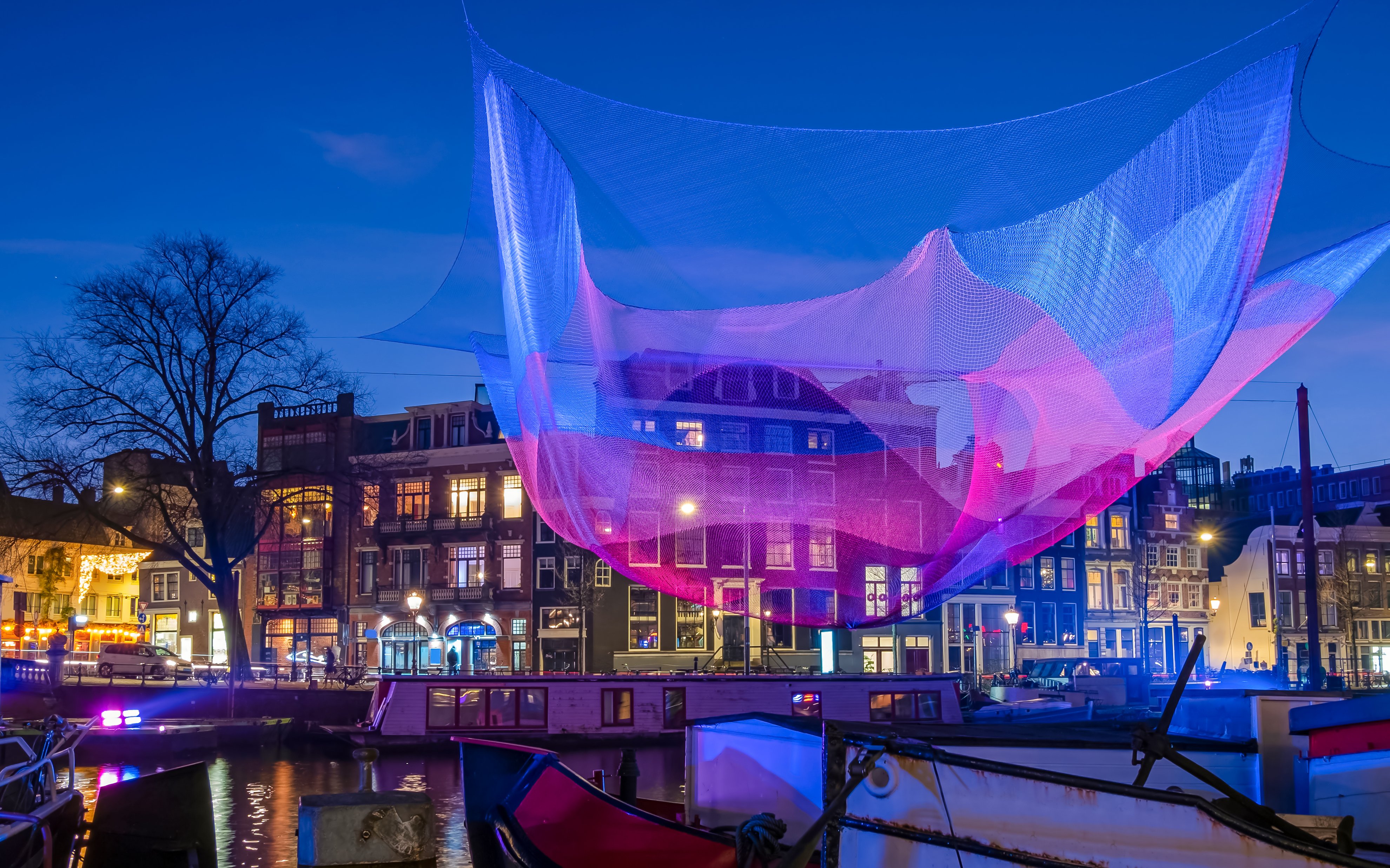 Colorful light installation over Amsterdam canal during the Amsterdam Light Festival.
