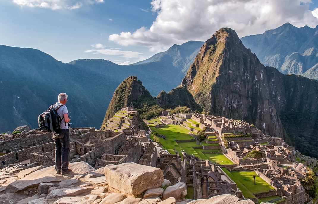 Traveler overlooking Machu Picchu ruins with Huayna Picchu in the background, Peru.