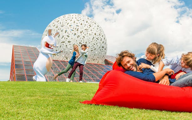 Families enjoying outdoor activities at Futuroscope with iconic architecture in the background.