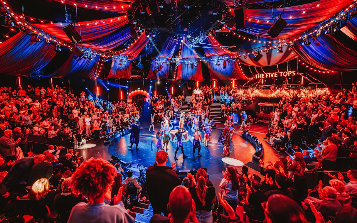 Stage performance of Come Alive Westend with vibrant audience and colorful lights.