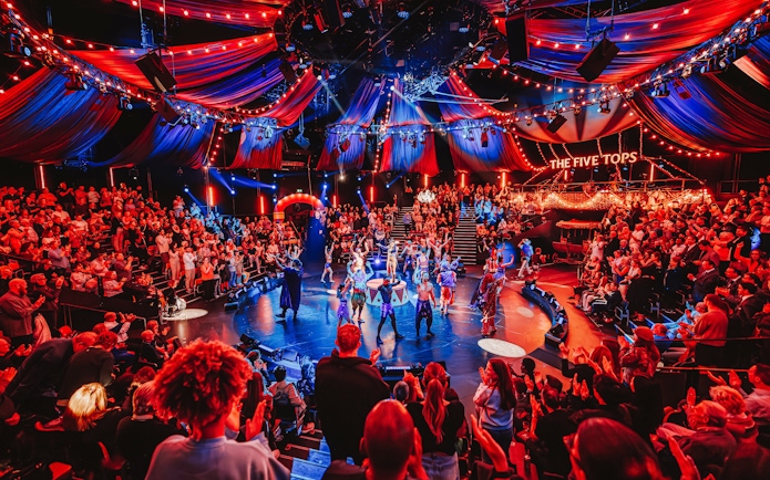 Stage performance of Come Alive Westend with vibrant audience and colorful lights.