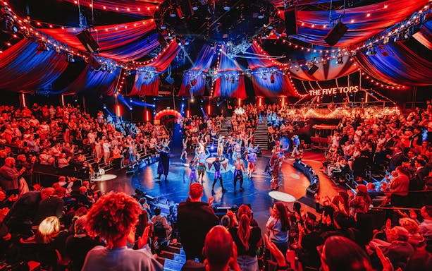 Stage performance of Come Alive Westend with vibrant audience and colorful lights.